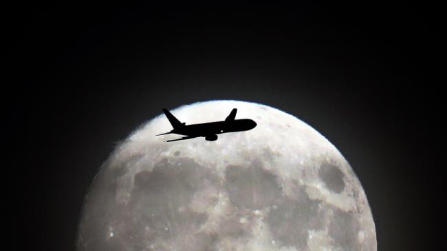 Plane silhouetted against the moon
