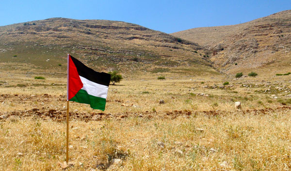 Palestinian flag with hills in the background