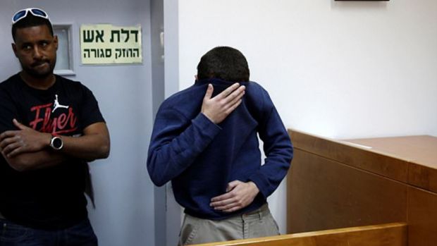 Kadar covering his face appearing in court
