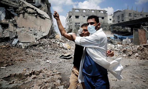A doctor covering a man's eye in front of rubble