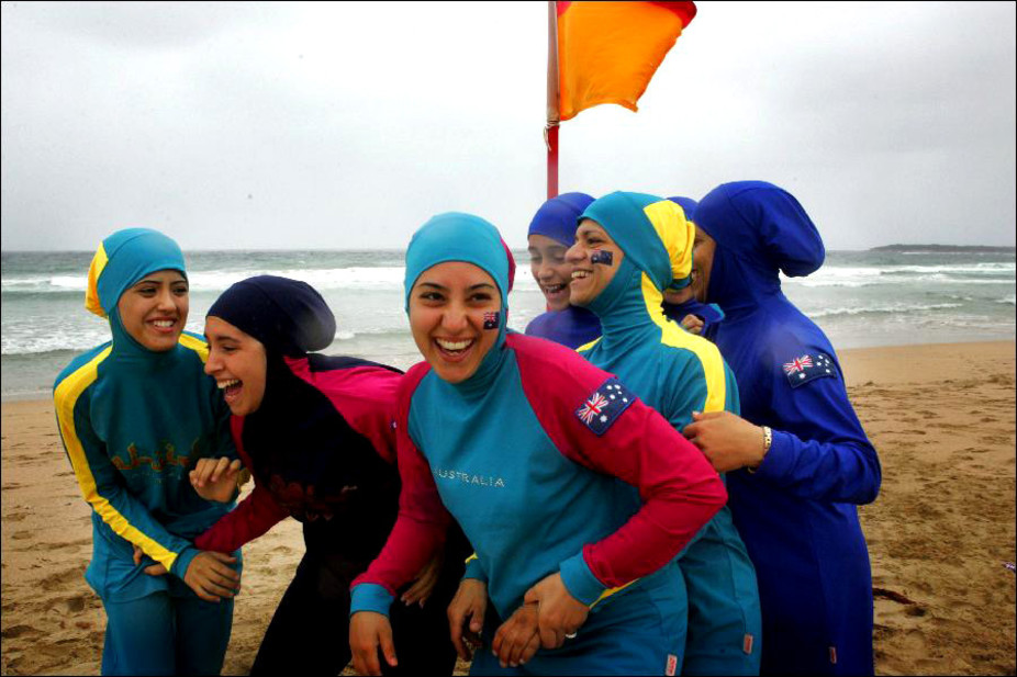 muslim girls in modest beachwear playing at beach