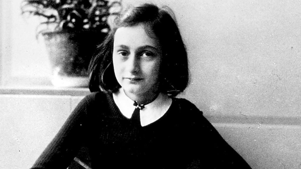 Anne Frank, pen in hand looking at the camera