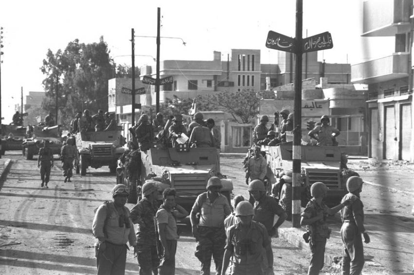 israeli forces standing around and in a convoy of armoured personnel carriers