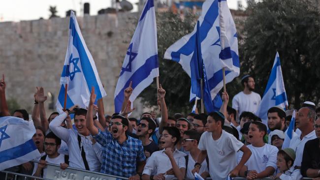 Israelis with flags protesting in front of old city walls