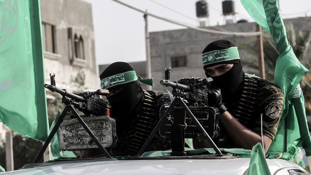 hamas fighters on top ofa truck with machine guns in a march in gaza