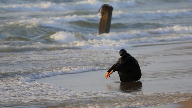 palestinian woman crouching on shore