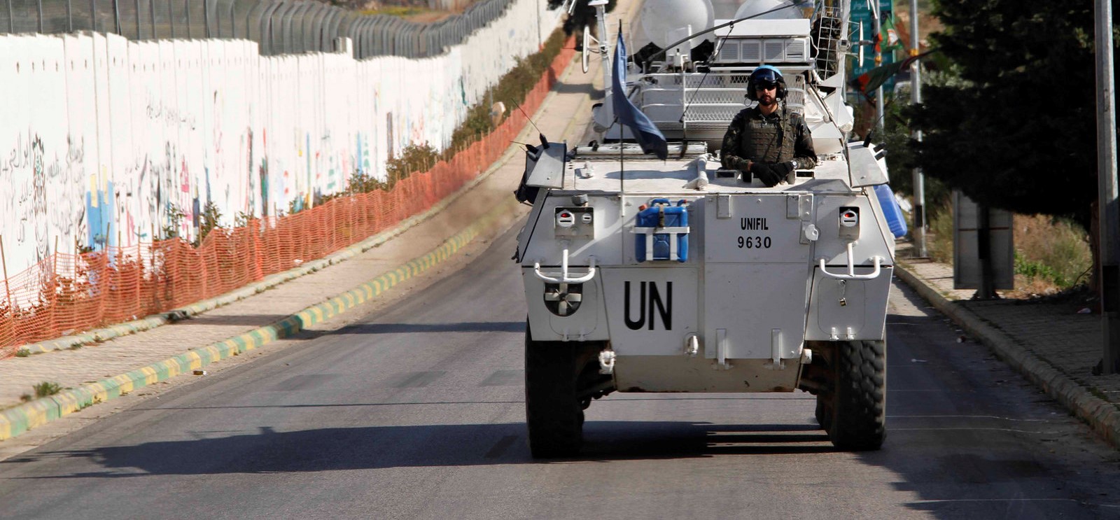 UN tank driving alongside a border fence