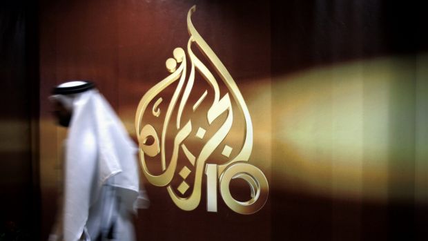 someone walking by al-jazeera logo on window