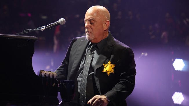 Billy Joel at piano with a yellow star of david on his chest