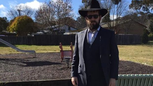 Rabbi standing awkwardly in front of a playground
