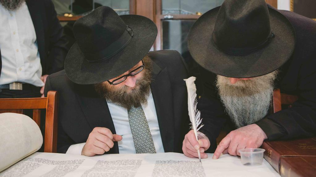 rabbis sitting finishing the torah scroll