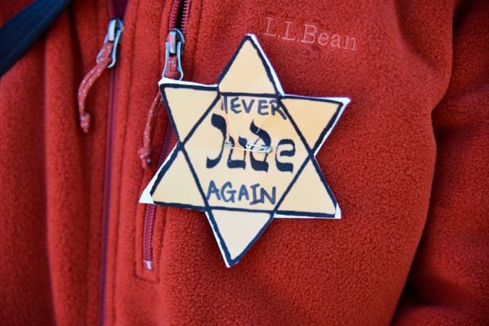 yellow star with 'never again' written on it on a modern jumper