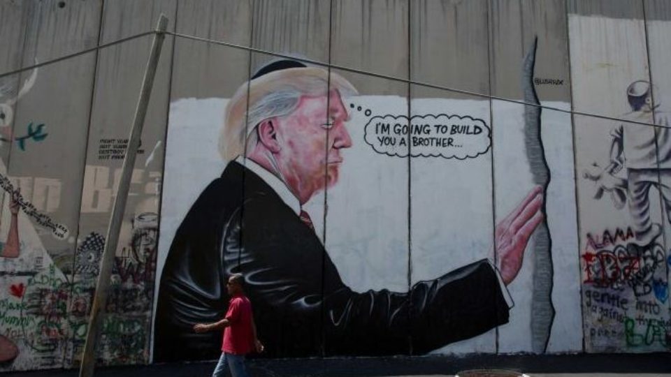 mural of trump touching the kotel and saying he will build another wall, drawn on the west bank separation wall