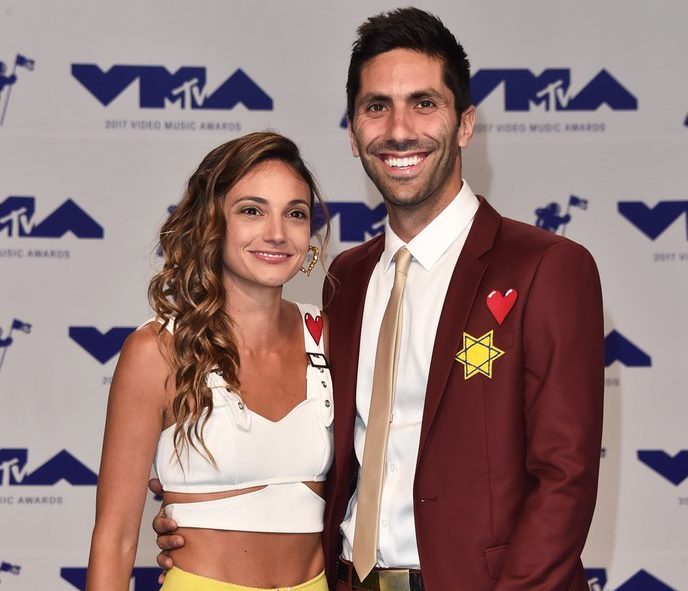 two celebrities posing on red carpet. man wearing a yellow star