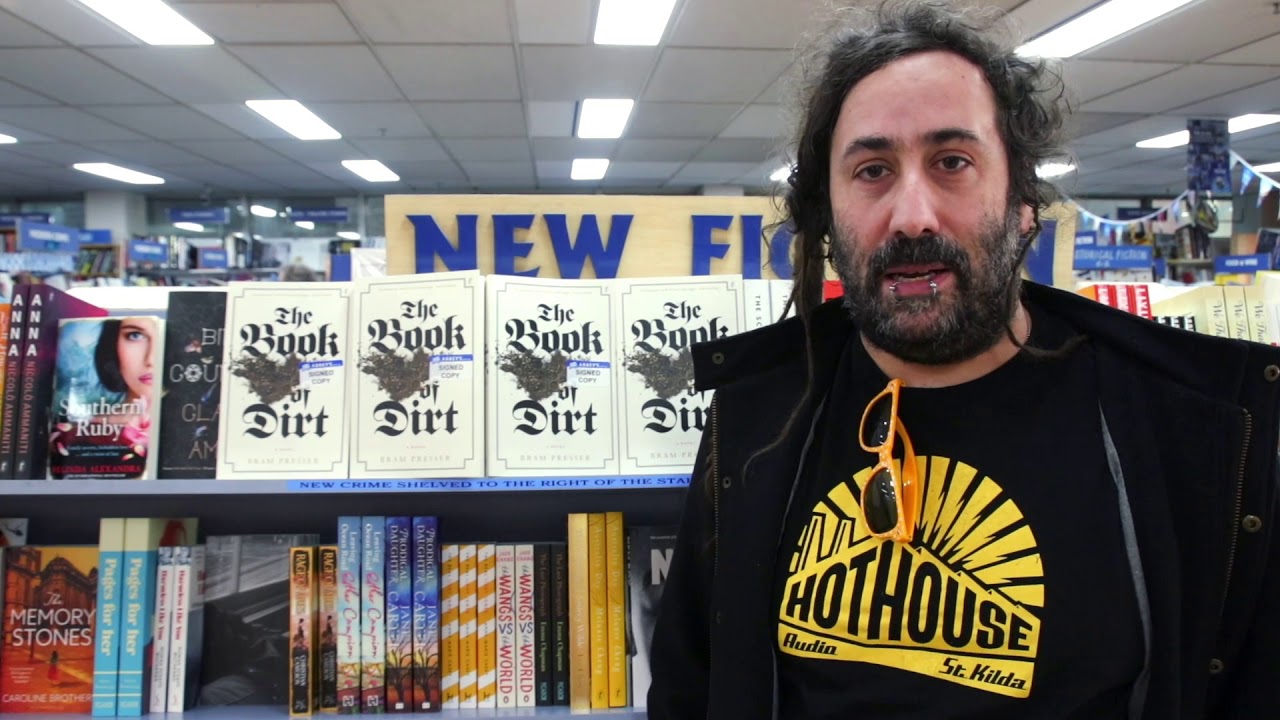 bram standing in front of his book on a shelf in a bookshop