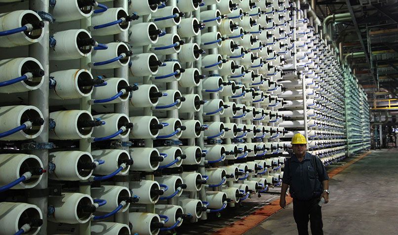 worker walking past rows of tanks in a desalination plant