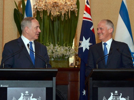 Prime Ministers Turnbull and Netanyahu at podiums talking and smiling at each other