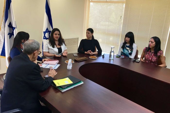 the victims sitting around a table at knesset meeting with someone