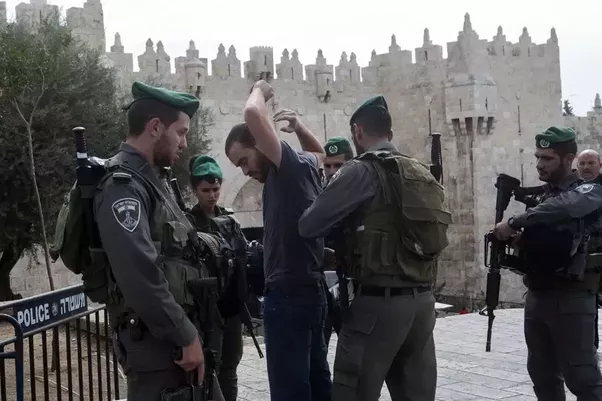 Man being searched by Israeli police outside walls of Old City