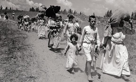 black and white photo of what appears to be refugees walking.
