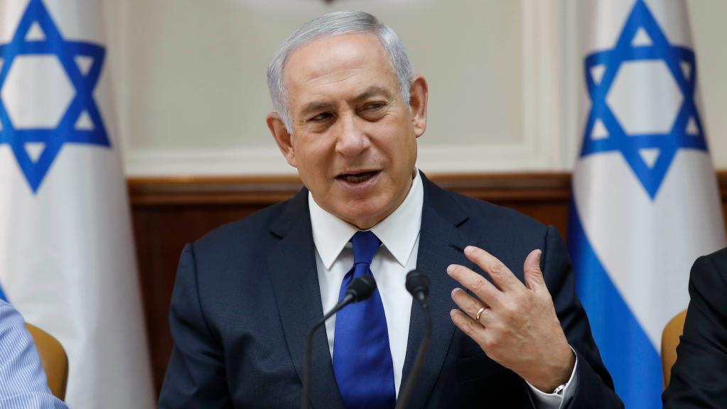 Prime Minster Netanyahu talking at a microphone and gesticulating with his hand