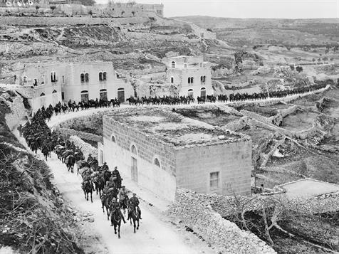 a line of light horse soldiers moving through a town in 1918.