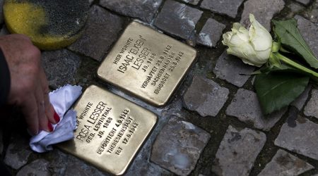 two memorial stones in the pavement, one being cleaned