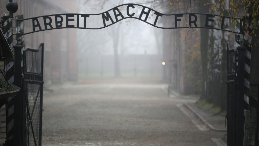 scary pic of the gates of auschwitz with the arbeit mach frei sign, with foggy background
