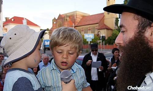 a rabbi interviewing two little kids with a microphone