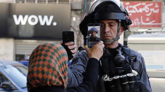 Israeli police officer taking a photo of a Palestinian woman, whilst she simultaneously photographs him.