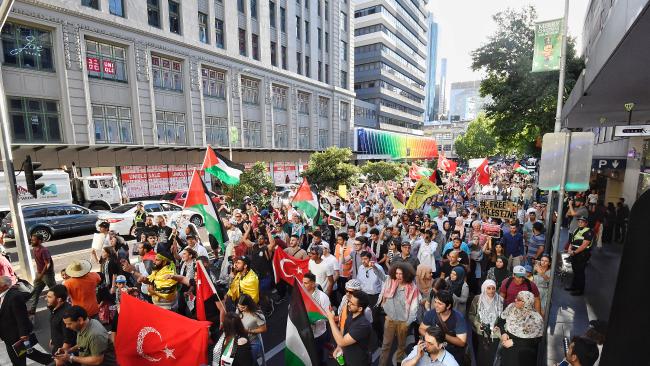 large crowd of protesters waving palestinian flags in melbourne street