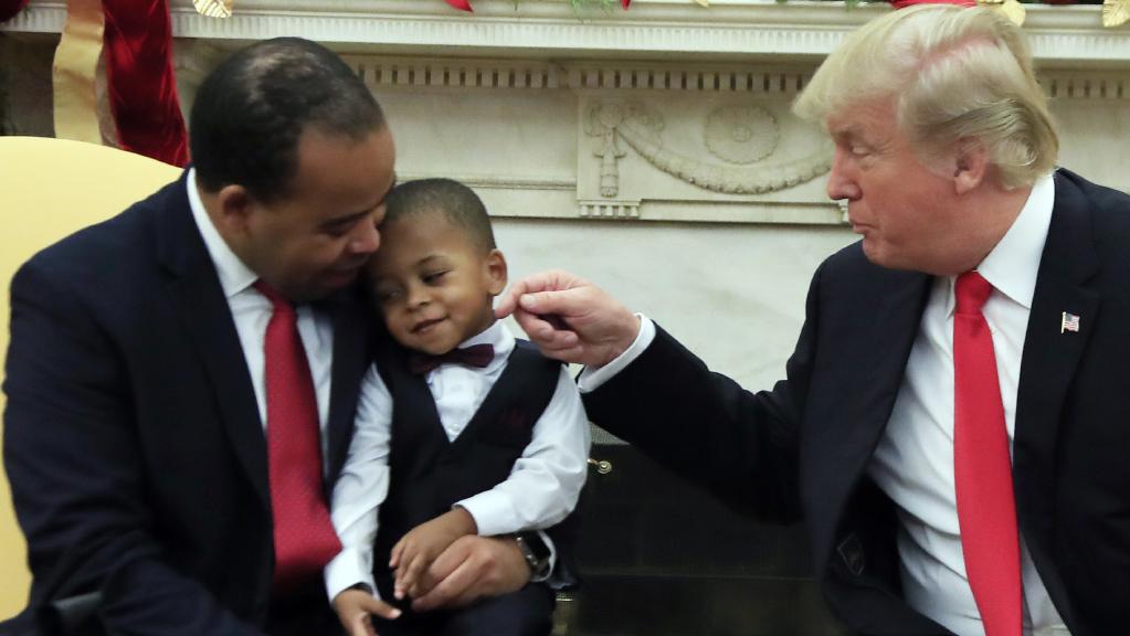 trump sitting with father and son and trying to touch boy on face