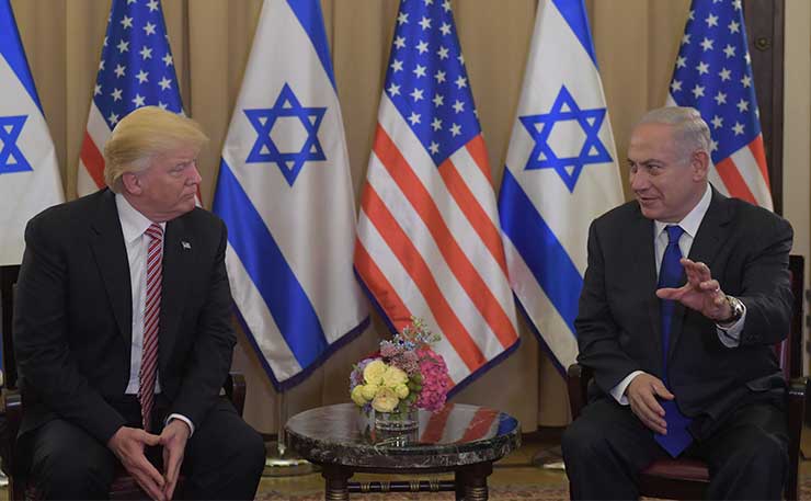Presidents Trump and Netanyahu seated, talking in front of american and israeli flags