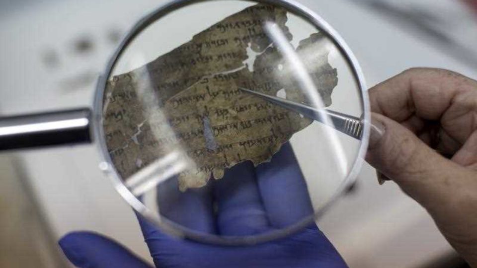 close up looking at small part of scrolls through magnifying glass