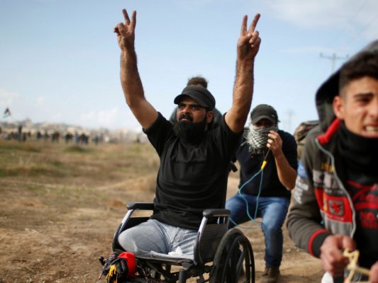 ibraheem in wheelchair making peace signs with both hands in the air