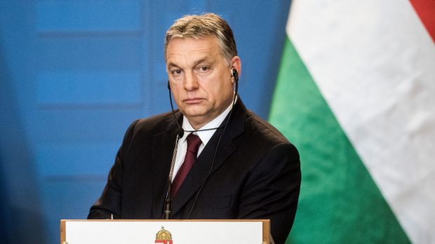 Hungarian prime minister at the podium with earphones in listening to translation