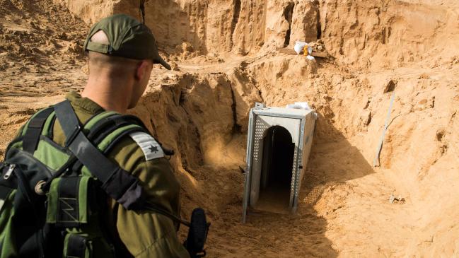 Israeli soldier in the foreground looking at a tunnel entrance