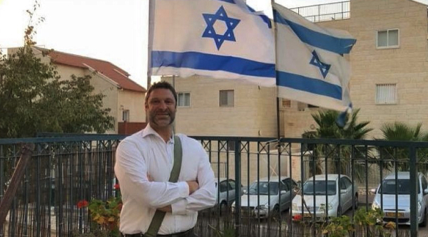 Ari Fuld posing in front of Israeli flags