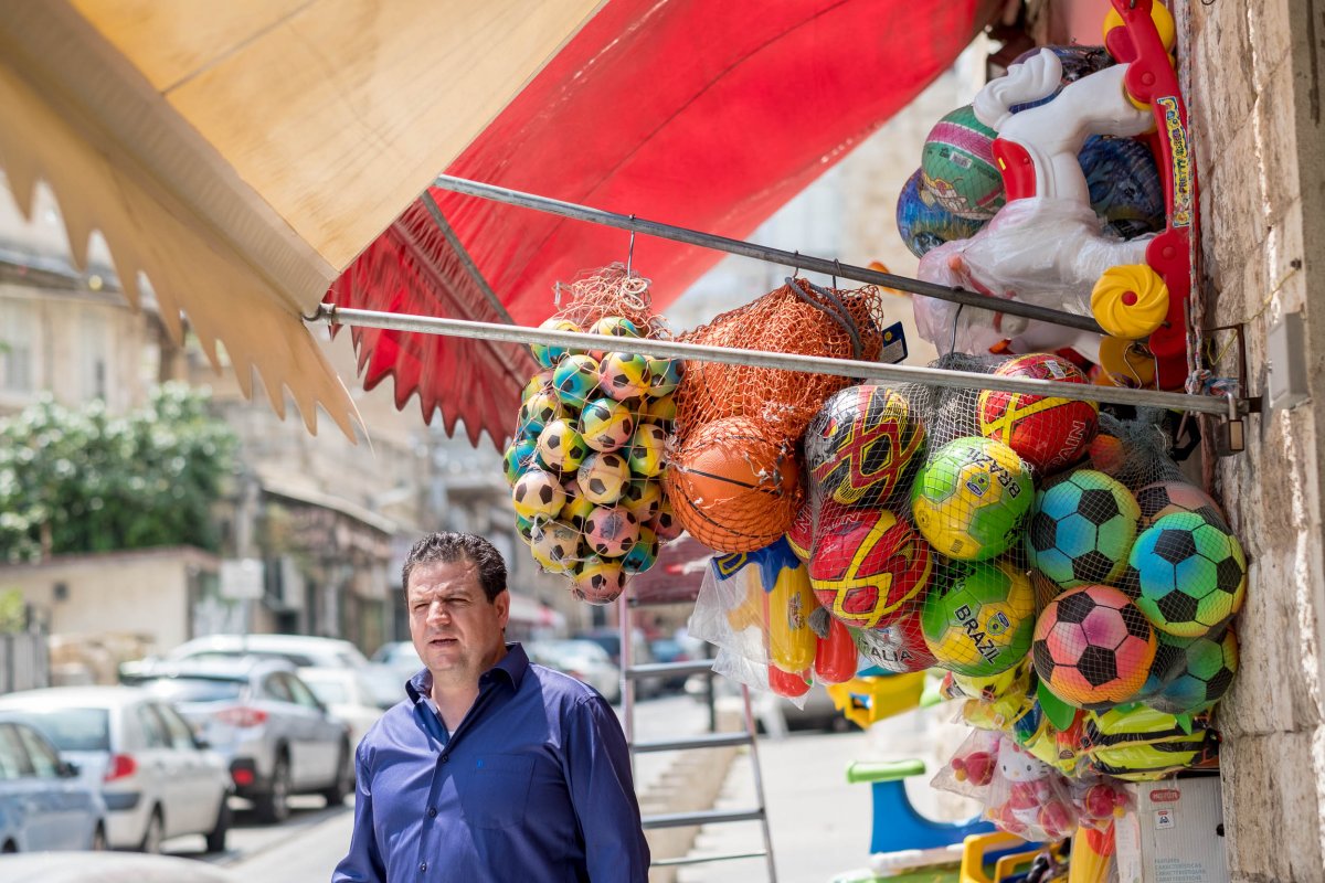 Ayman standing on the street in front of a toy shop with lots of balls hanging outside