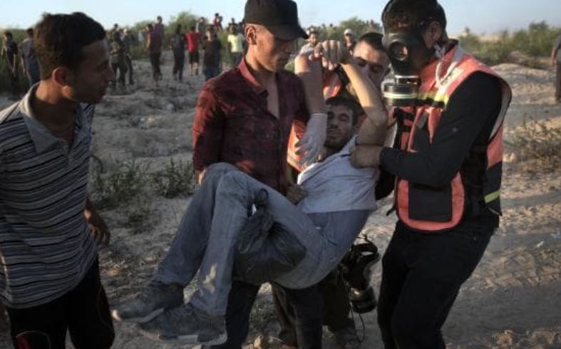 palestinian man who appears injured being carried by others and medics