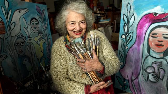 Mirka holiding her brushes standing near her art