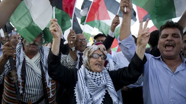 old woman at rally with people and lots of palestinian flags